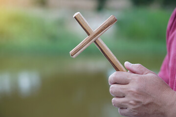 Close up Christian man holding a wooden crucifix to pray.  Concept, Christian worship. Faith,...