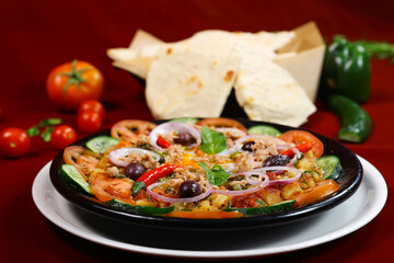 Colorful Tunisian Salad with Poached Eggs, mashed potatoes, cucumber, onion, mint, tomato, vegetables, poached eggs, and olives in plate isolated on red background side view of arabic food