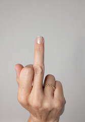 female hand with a middle finger pointing at the camera in front  light grey background point of view ring
