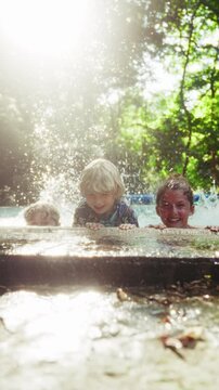 Three Kids Flutter Kicking The Water Making Splashes In The Pool