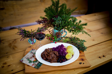 ready to eat and served on a white plate on a wood table - goulash from venison meat with potatoes,...