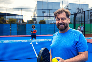 Portrait of man playing padel with her female friend on outdoor court.