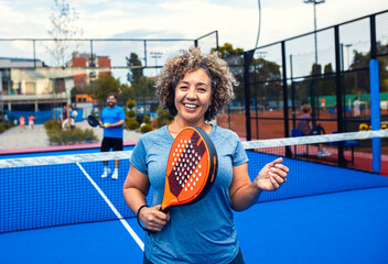 Portrait of woman playing padel with her friend on outdoor court.