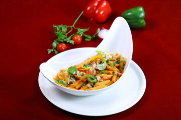 penne arrabiata pasta topping with coriander, capsicum and tomato sauce served in dish isolated on red background side view of italian food