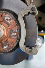Closeup a disassembled car brake system during maintenance. Front disc brake of a car with a removed wheel. Shallow focus.