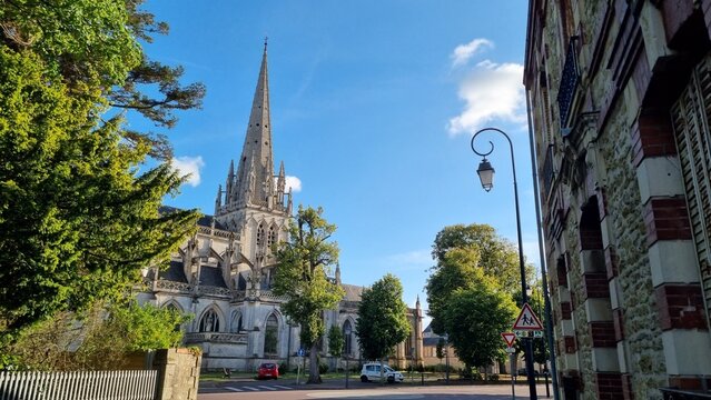 CARENTAN, NORMANDY, FRANCE - JULY 23, 2024: Carentan church. Historic church towers over the streets of a quaint town filled with greenery on a sunny day