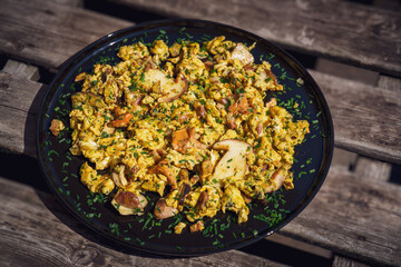 ready to eat - scrambled eggs and chanterelles on a black plate