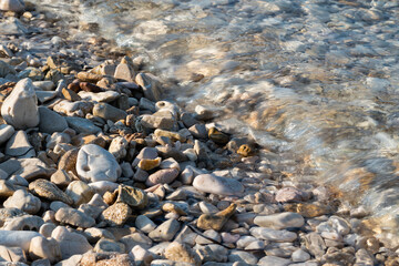 Sea water covers beach stones, bubbles in water