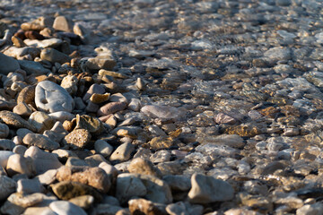 Small wave splashes over pebble on beach