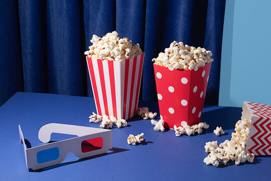 Cinema night essentials with popcorn and 3D glasses on blue