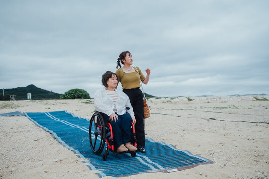 車椅子に乗った日本人女性が友人の女性と夏の沖縄を旅を楽しんでいる