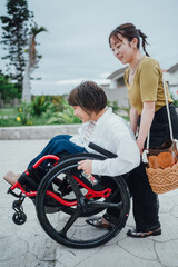 車椅子に乗った日本人女性が友人の女性と夏の沖縄を旅を楽しんでいる