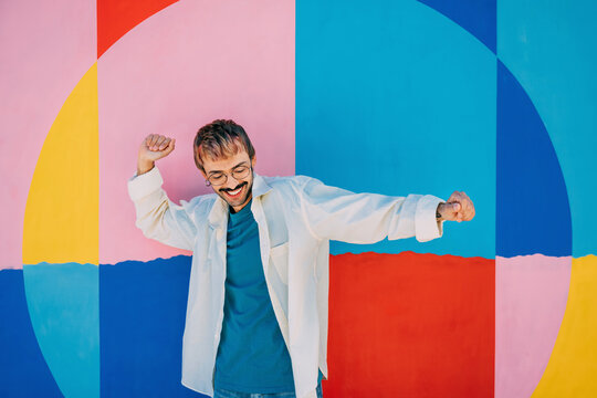Joyful man posing against a vibrant multicolored backdrop