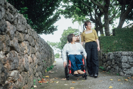 車椅子に乗った日本人女性が友人の女性と夏の沖縄を旅を楽しんでいる