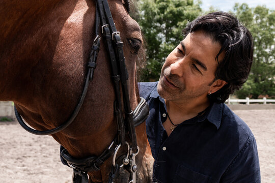 Groom caring for his horse at an equestrian center