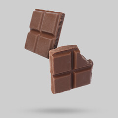 Pieces of sweet chocolate falling on grey background