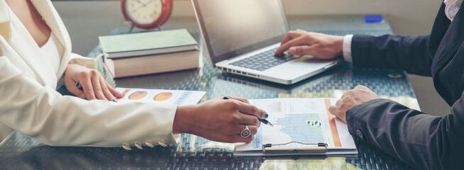 Banner Business and Financial Planning Concept. Two business man and woman discuss financial. Hand Financial advisor plan and point chart report and graph, using laptop in home office during meeting.