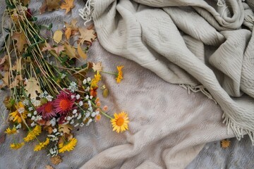 Beige linen blanket with wildflowers and autumn leaves. Top view and flat lay with copy space, aesthetic photo in boho style.