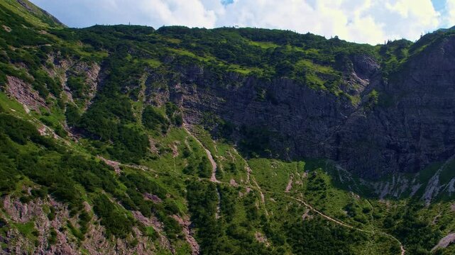 4K Aerial Drone video of the most beautiful mountain lake Schrecksee in Bavarian Alps with the cows feeding on lush green grass on a sunny day with blue skies and rocky hill tops surrounding
