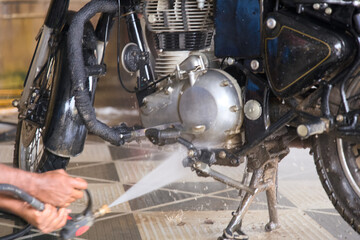 Fototapeta premium A person washing a motorcycle engine with a pressure washer at a bike cleaning station in the morning