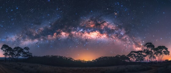 Naklejka premium Mystical Milky Way: Astounding Image of Cosmic Beauty Blanketing Forest in Night Sky - Perfect for Astrophotography Enthusiasts