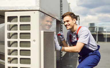 Young professional technician wearing uniform installing and fixing air conditioner using...