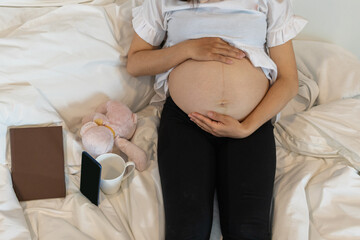 The expectant mother puts her hands on her belly to communicate with her unborn child and wait for...