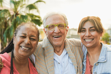 Happy elderly people smiling on camera with city in background during fall time - Joyful senior...