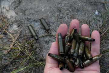 Bullet casings in the human hand. Empty shell casings on the soil. Ukraine is a danger zone.