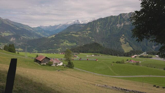 Leysin, Vaud, Switzerland - August 8 2023: Beautiful view on alpine valley with green pastures, the Berneuse cable car and the Les Diablerets mountain range in the background in summer