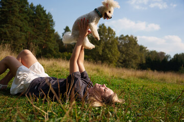 The beautiful woman lies on the grass and hug with her dog. The girl have a fun tome with the dog....