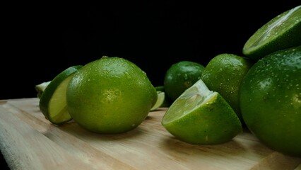 Close-up, a vibrant slice of fresh lime rests upon a rustic wooden cutting board, exuding freshness and vitality. The translucent membranes of the green lime slice placed on cutting board. Comestible.