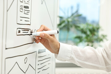 Developing UI design. Woman drawing website wireframe on whiteboard indoors, closeup