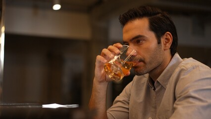 Sitting smart man drinking alone of cocktail Old fashioned waiting friends or couple at bokeh lighting at luxurious beverage counter nightclub at pub and restaurant on Friday meeting night. Vinosity.