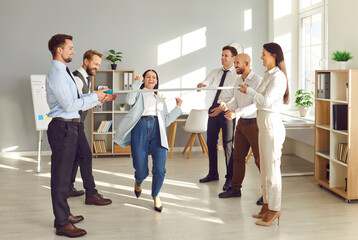 Funny office team event for fun, motivation and promote business cooperation, limbo dance contest. Woman passing forwards under low bar, amusing, entertaining, enjoyable work rest, playful businessmen