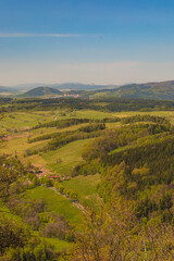 Obraz premium Beautiful green landscape of Walbrzych mountains with blue sky seen from top of Rogowiec mountain 870 meters above the sea level with ruins of old castle