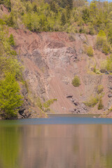 Peaceful forest Kamyki lake after old quarry reflecting the vibrant green foliage under a clear blue sky, creating a serene and tranquil atmosphere © Pawel-Wierzchowski