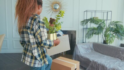 Young diverse couple rejuvenates their living room by adding indoor plants and rearranging furniture. The bright space radiates warmth and creativity, blending nature with modern decor effortlessly.