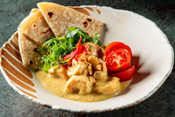 close-up of a dish with creamy shrimp curry, garnished with fresh herbs, red chili, and served with flatbread on a decorative plate. Perfect for food photography, culinary blogs, and recipe websites.