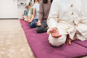 Fototapeta premium Yoga instructor and senior women practicing meditation in a row during a mindfulness session.