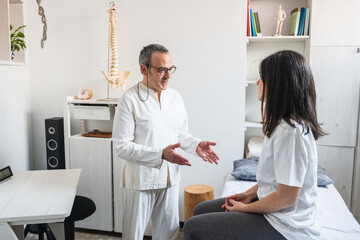 Obraz premium Therapist explaining treatment to a patient after a craniosacral therapy session in the clinic.