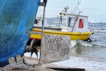 The rudder and propeller of a fishing boat against the background of another fishing boat pulled up...
