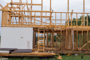 Construction of a house outside the city. The frame of the house on stilts. The concept of life in the village. There are fields and woods around.