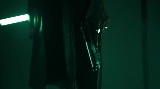 Woman agent in a leather coat holding an m9 handgun in a dark room lit by led lamps