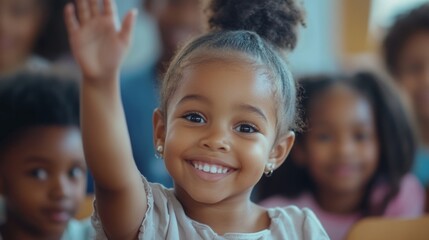 Fototapeta premium A young African American female child raises her hand to ask or answer a question. Smiling and sitting in a classroom interior with other pupils. Indoors education, kindergarten.