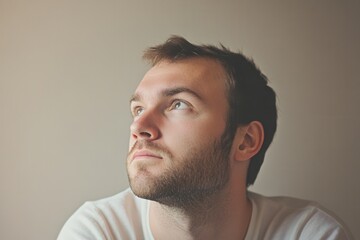 Obraz premium A thoughtful man with a serious demeanor looks up, lost in deep contemplation, surrounded by warm light in a quiet space. Generative AI