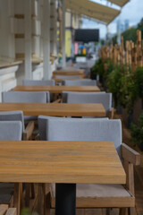 Close-up view of empty wooden tables of sidewalk cafe or street restaurant with bamboo fence in the morning. Focus on table surface. Copy space for your text or decoration. Food  business theme.