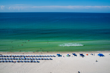 When the weather is nice, people gathering on Panama Beach City, Florida. The city is famous for its calm, clear and warm water. Background of umbrellas, waves, tiny people on different blue colors