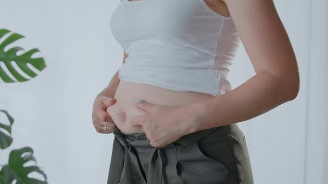 Women's body fat belly, woman's hand slapping excessive belly fat. 