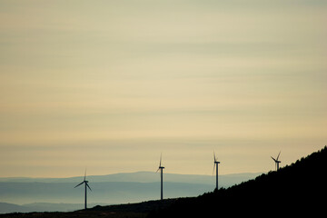 Obraz premium silhouette of a mountain range with wind turbine generators at sundown
